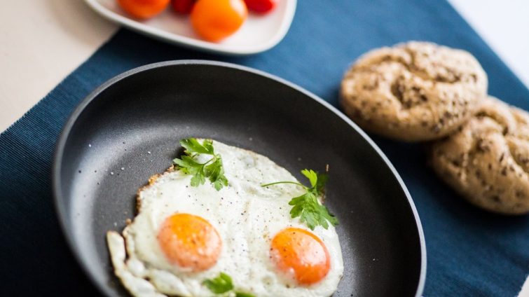 two fried eggs in a frying pan next to a plate of cookies